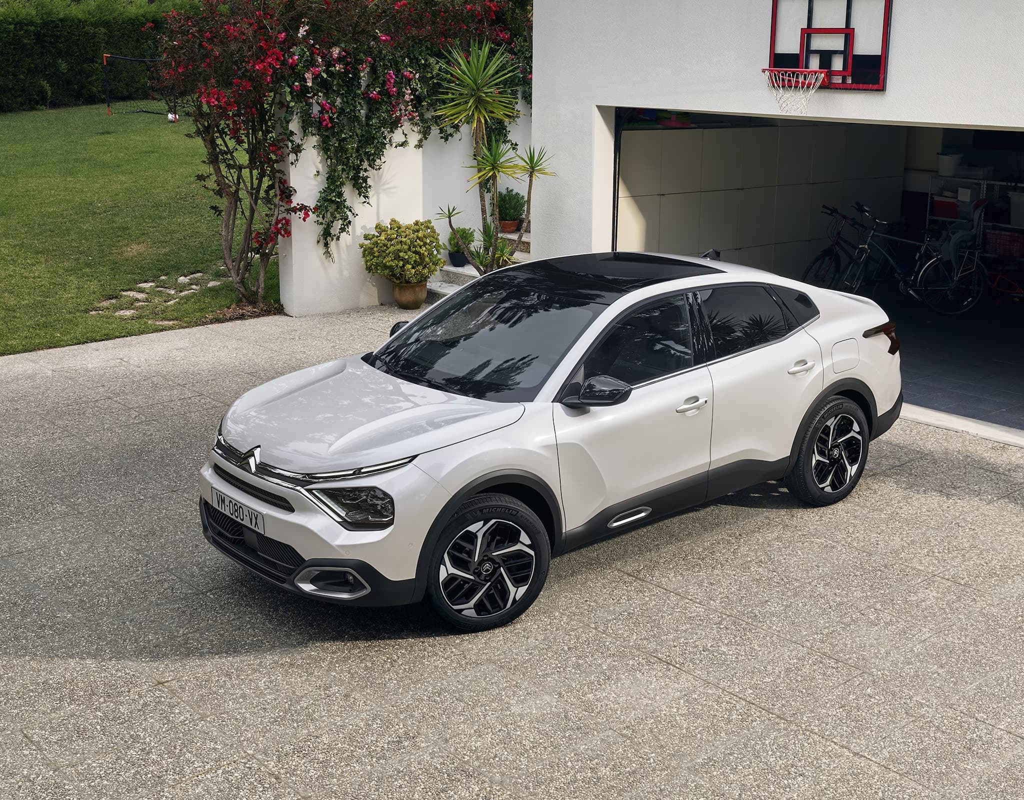 Citroën ë-C4 X Électrique garée devant la porte de garage d'une maison