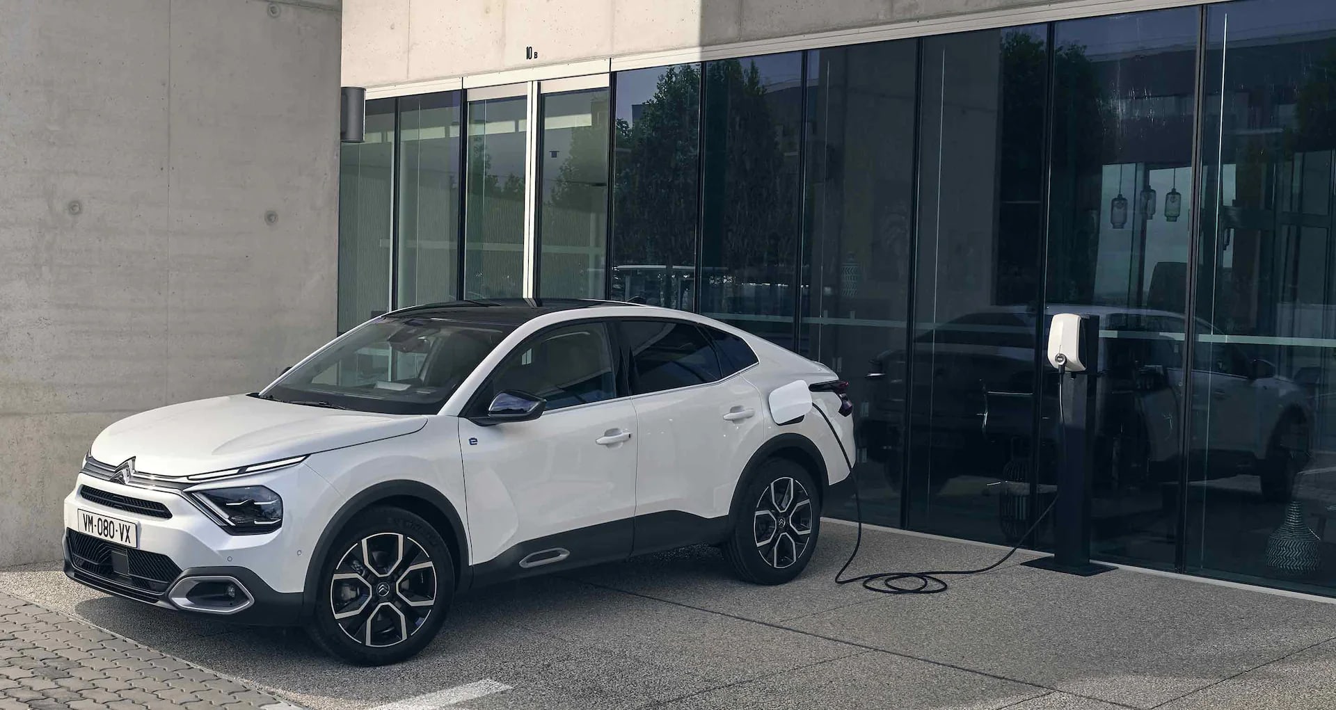 Citroën ë-C4 X Électrique en recharge devant l'immeuble d'une entreprise